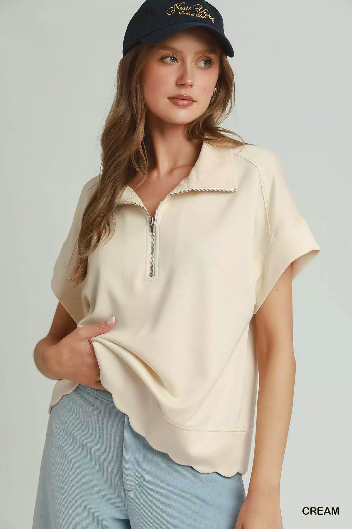 Cream half-zip pullover with scalloped hem and short sleeves