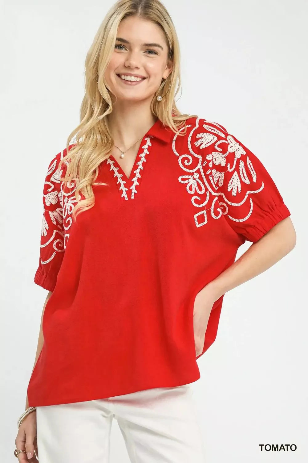 Red blouse with white floral embroidery on V neckline and decorative sleeves.