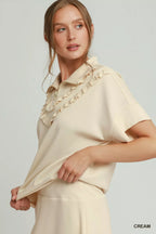 Cream quarter-zip short-sleeve top with layered ruffle collar and stitched trim detail