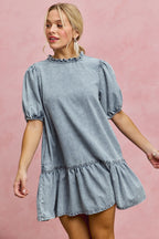 Light wash denim mini dress with ruffled neckline and puff sleeves, short tiered skirt