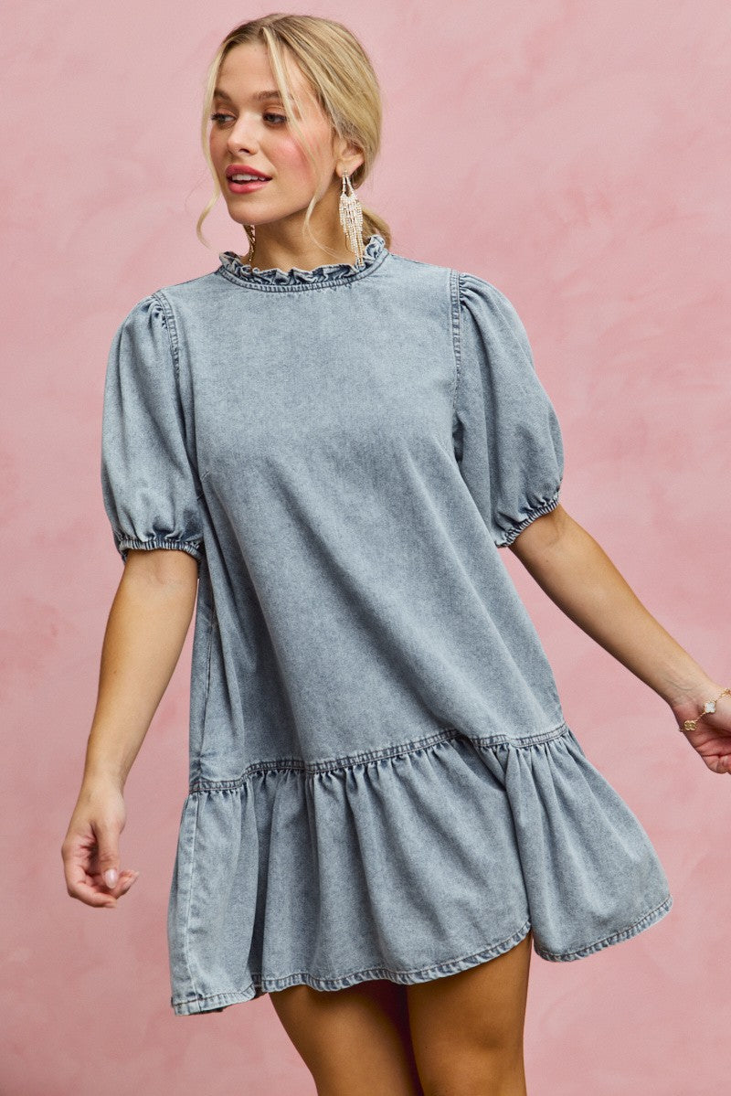 Light wash denim mini dress with ruffled neckline and puff sleeves, short tiered skirt