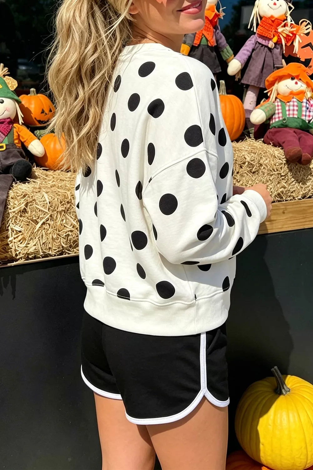 White sweatshirt with black polka dots, round neckline, and long sleeves; relaxed fit