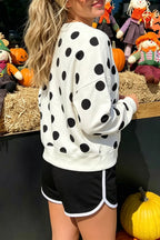White sweatshirt with black polka dots, round neckline, and long sleeves; relaxed fit