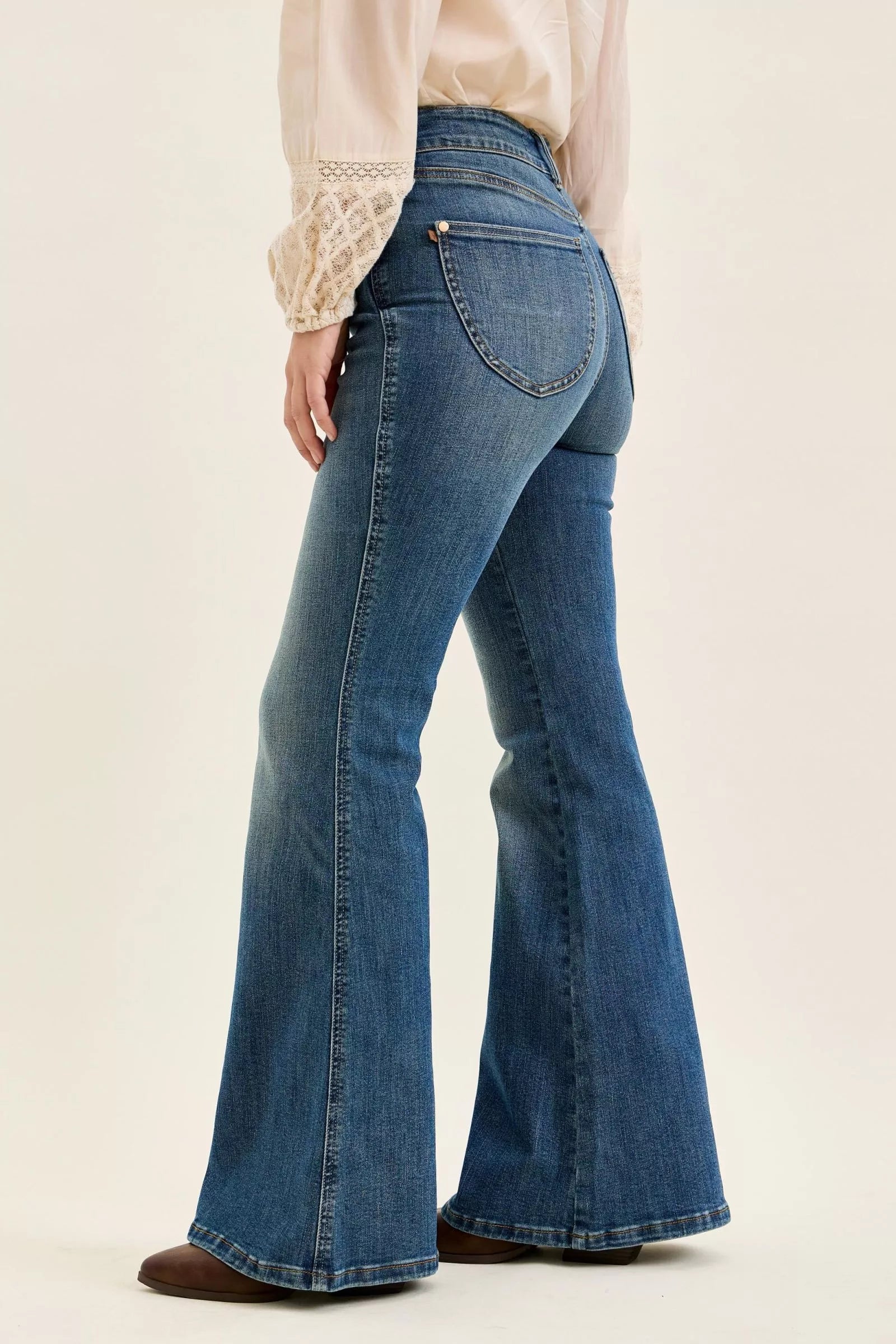 High-waist flare jeans in blue denim, side profile with front seam details and belt loops