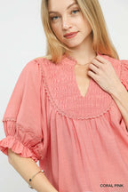 Coral pink smocked yoke blouse with ruffled sleeve cuff and keyhole neckline