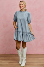 Light-wash denim mini dress with ruffled neckline and puff sleeves, tiered skirt