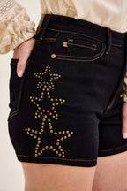 Close-up of high-waist black denim shorts with gold star stud embellishment