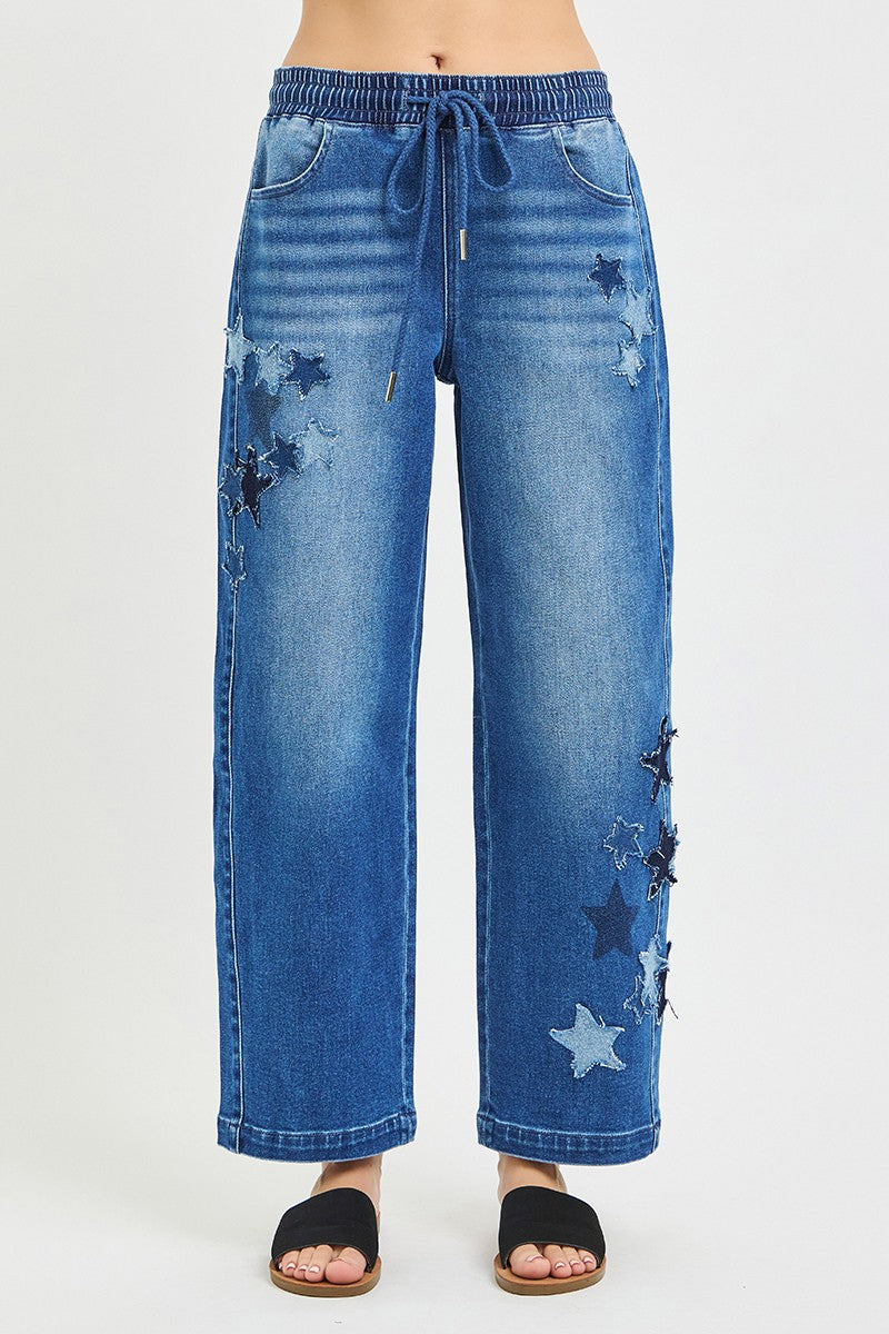 Front view of medium-wash cropped barrel jeans with drawstring waist and star patch details