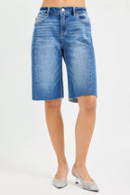 Medium-wash denim jorts with raw frayed hem and classic five-pocket design