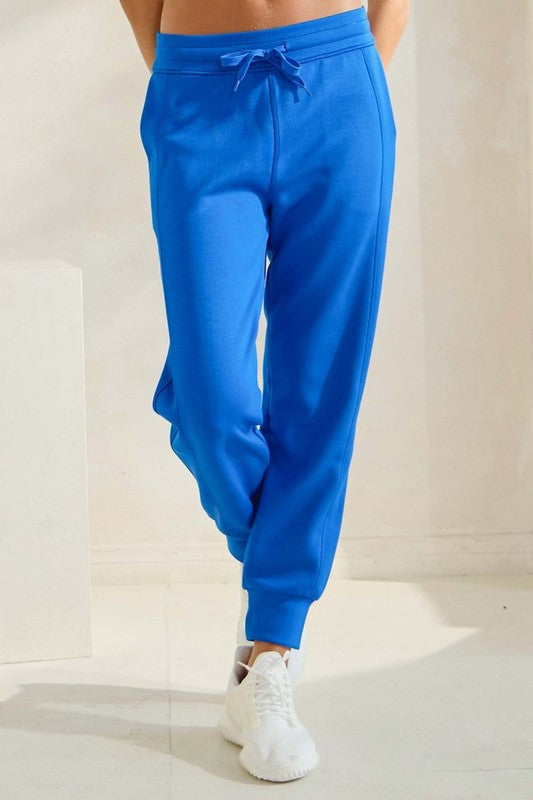 High-waisted blue joggers with drawstring waist and tapered ankle cuffs, side pockets