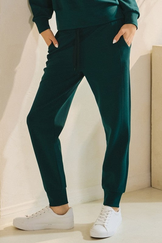 High-waisted joggers in dark green with drawstring and ankle cuffs, side pockets