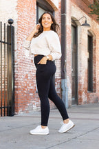 Black high-waisted full-length leggings on a model, side-step stance.