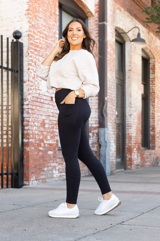 Black high-waisted full-length leggings on a model, side-step stance.