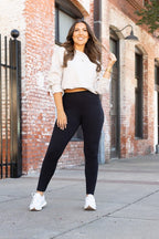 Black high-waisted full-length leggings on a model, front view with hands down.