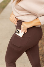 Brown crossover leggings showing a side pocket with a device inside