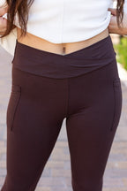 Brown crossover waistband leggings with flat front and side pocket detail