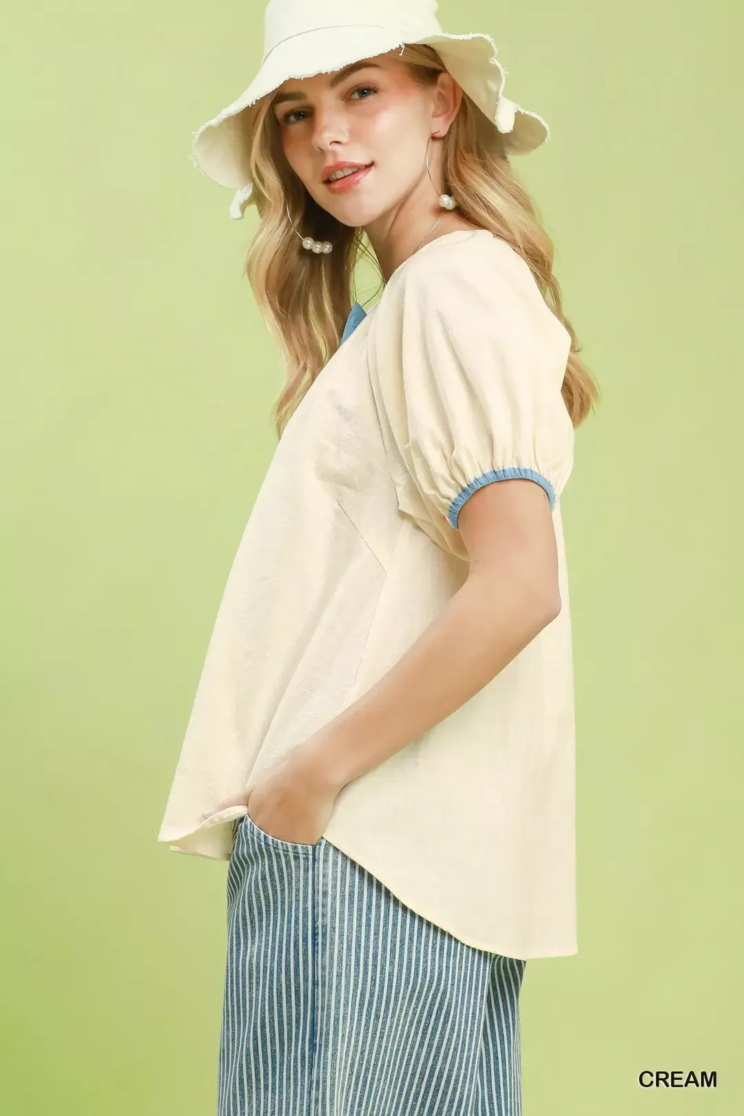 Cream button-front blouse with blue trim on short puff sleeves, side view