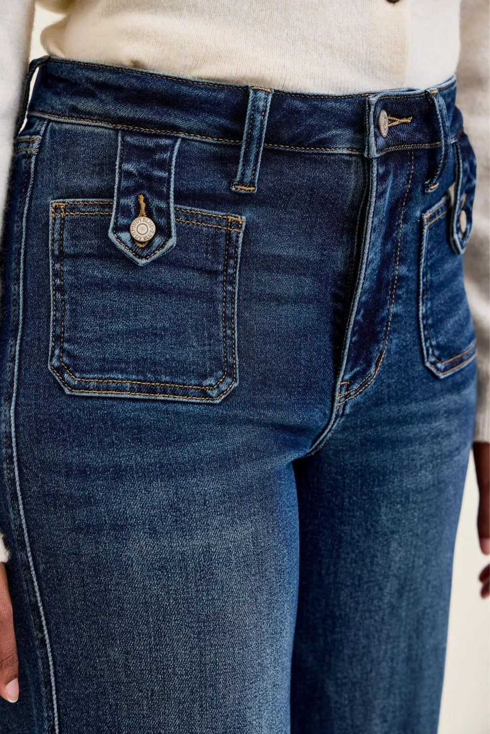 Dark indigo jeans close-up: patch pocket with logo tab and belt-loop waistband