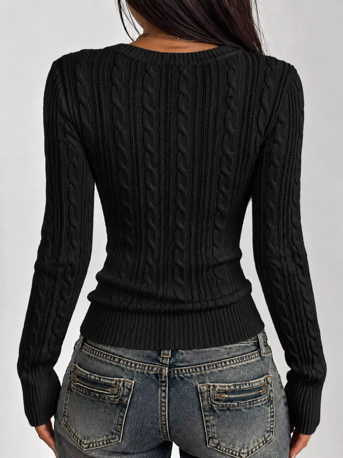 Black cable-knit sweater back view with vertical cable texture and long sleeves