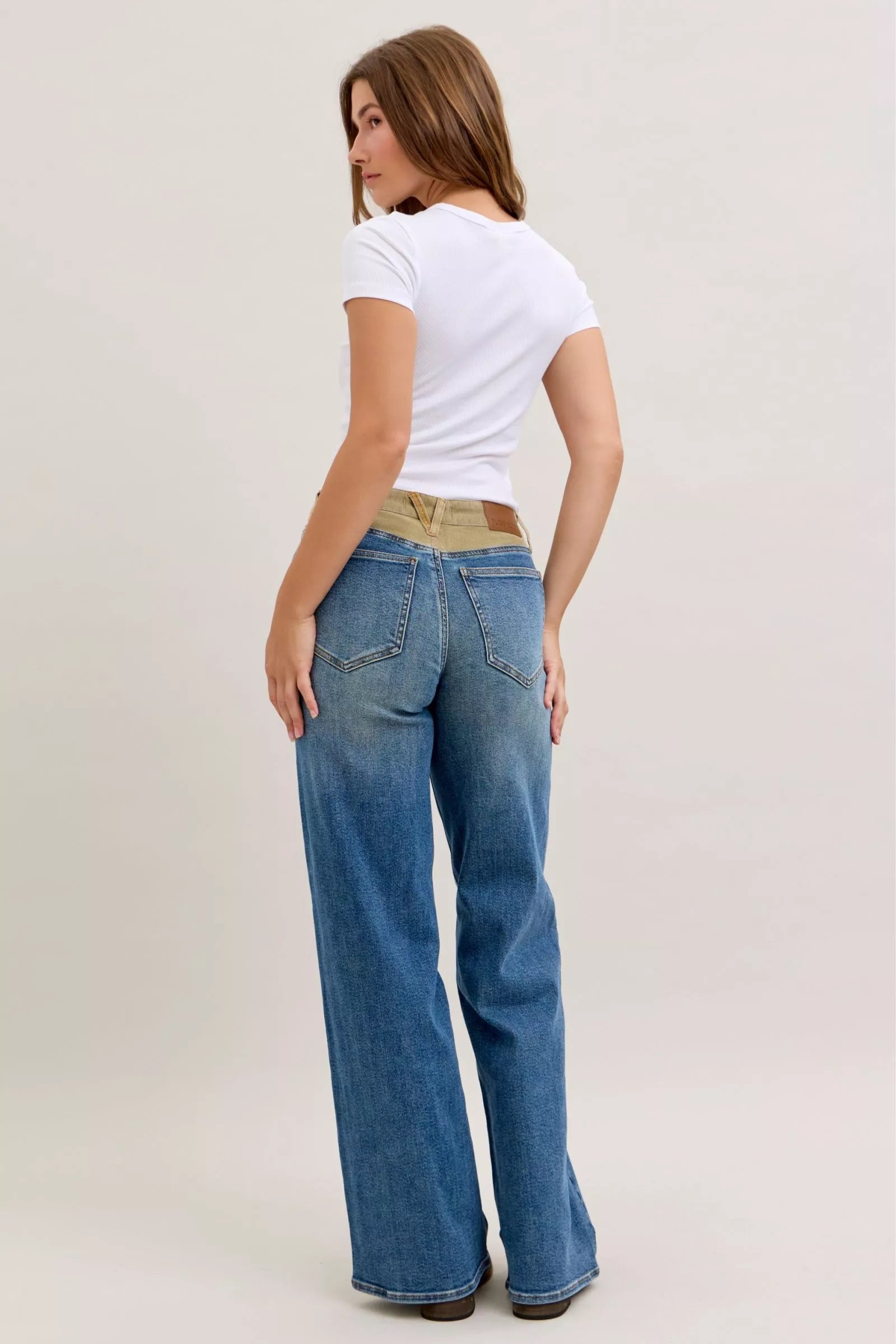 Women’s mid-rise straight jeans in blue denim with tan corduroy waistband, back angle view