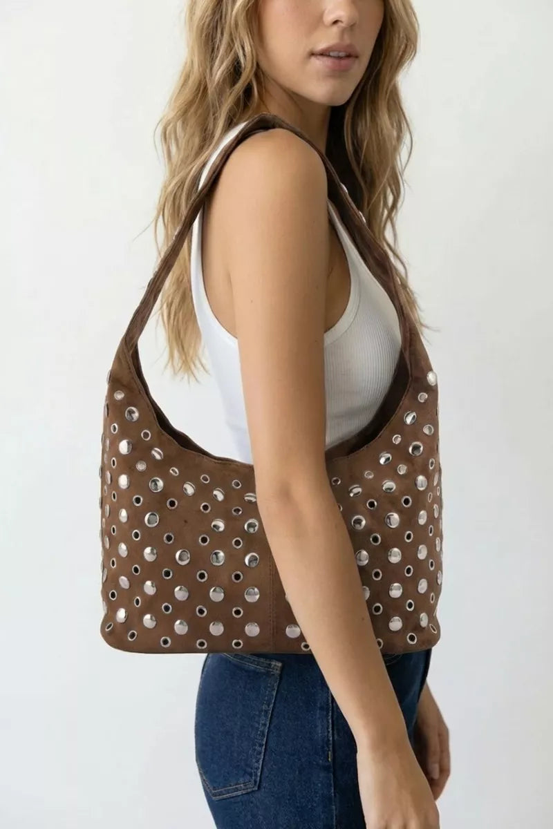 Brown studded shoulder bag worn on shoulder with silver grommet pattern
