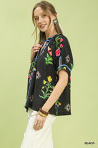 Black botanical print button blouse with blue piping, short sleeves and v-neck
