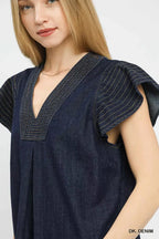 Dark denim cap-sleeve V-neck top close-up showing stitched trim and texture