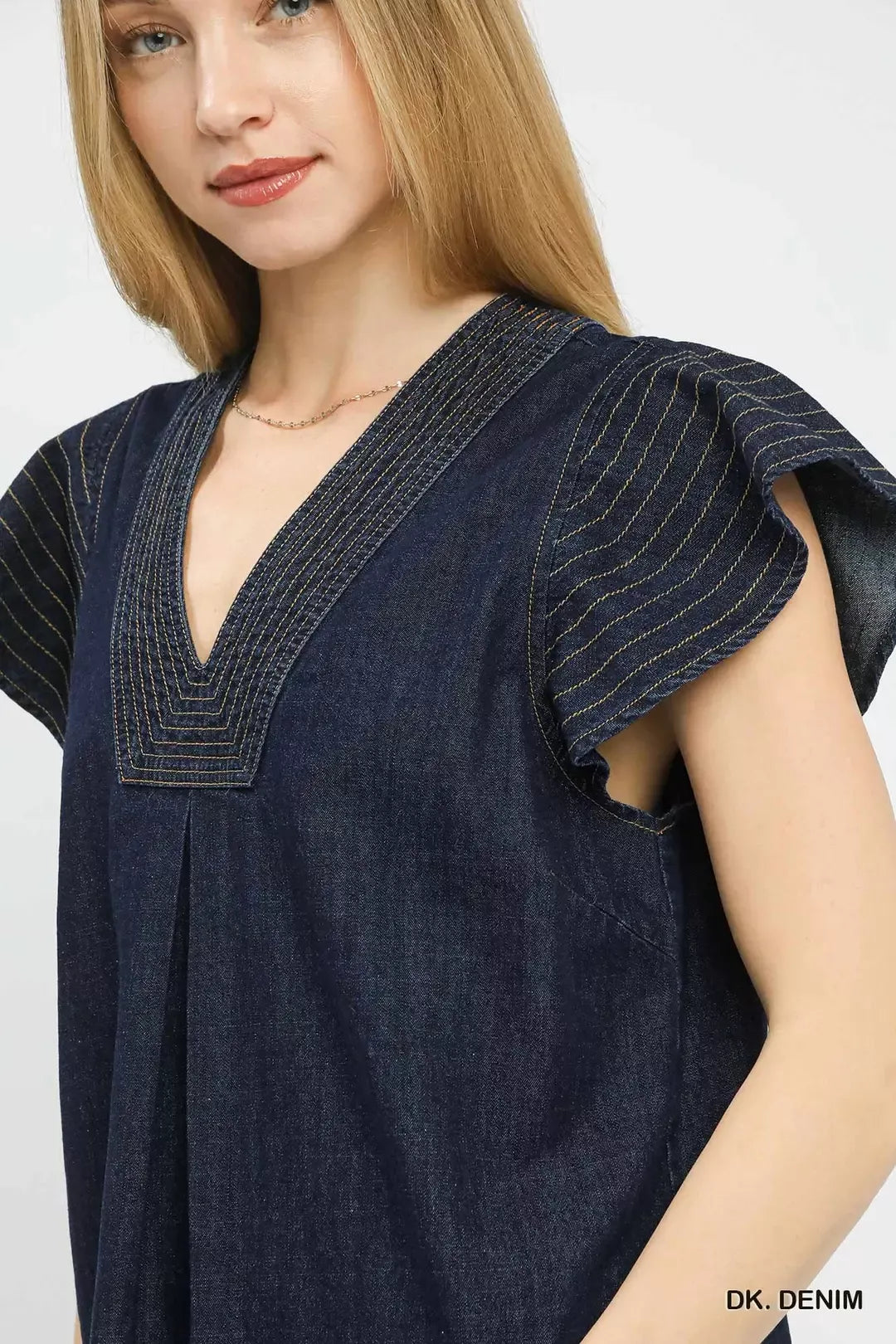 Dark denim cap-sleeve V-neck top close-up showing stitched trim and texture