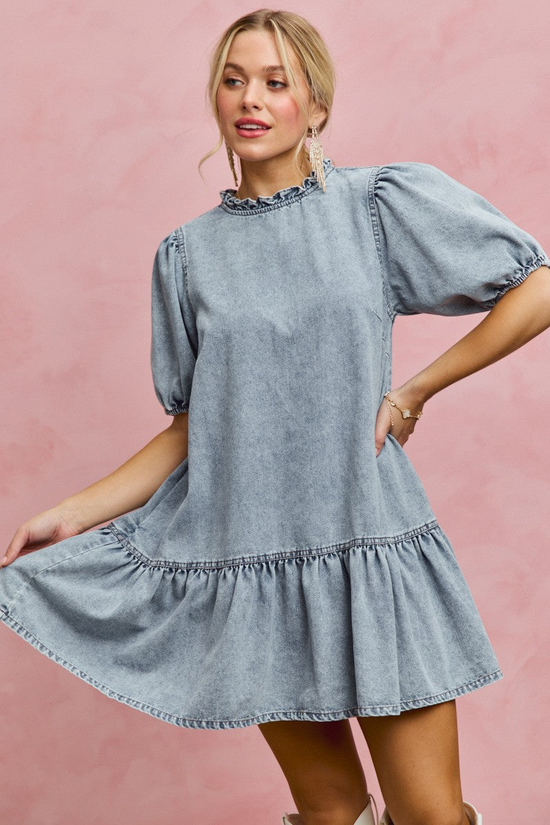 Light wash denim mini dress with ruffled neckline, puff sleeves, and flared tiered hem