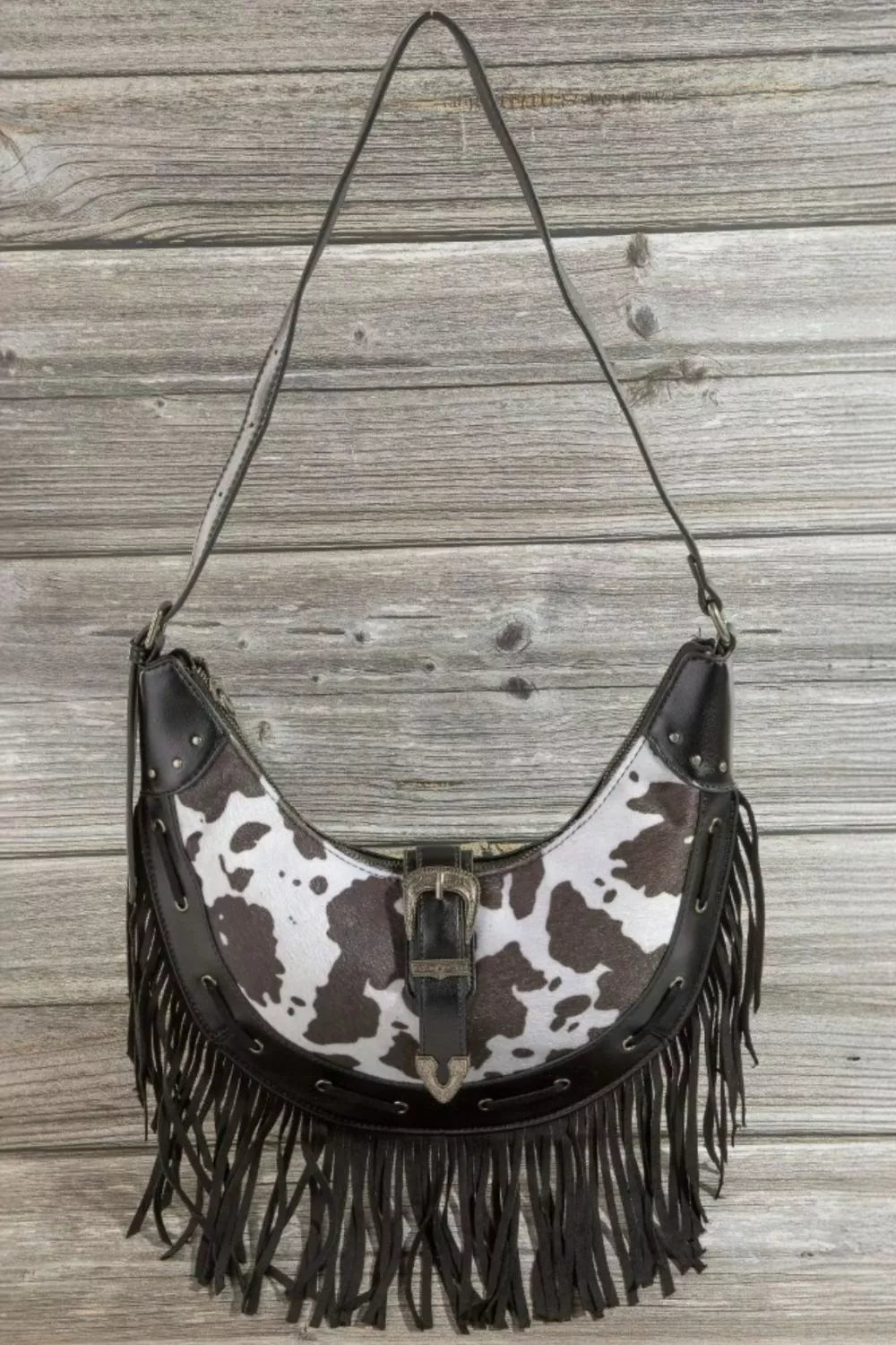 Cow print faux leather fringe hobo bag, black strap, centered metal buckle detail