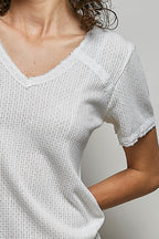 Off-white knit top close-up with lace-trim V-neck and textured short sleeves