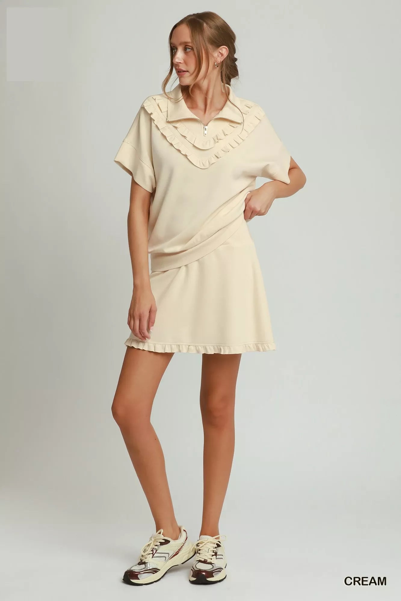 Cream quarter-zip ruffle-collar short-sleeve top with curved hemline