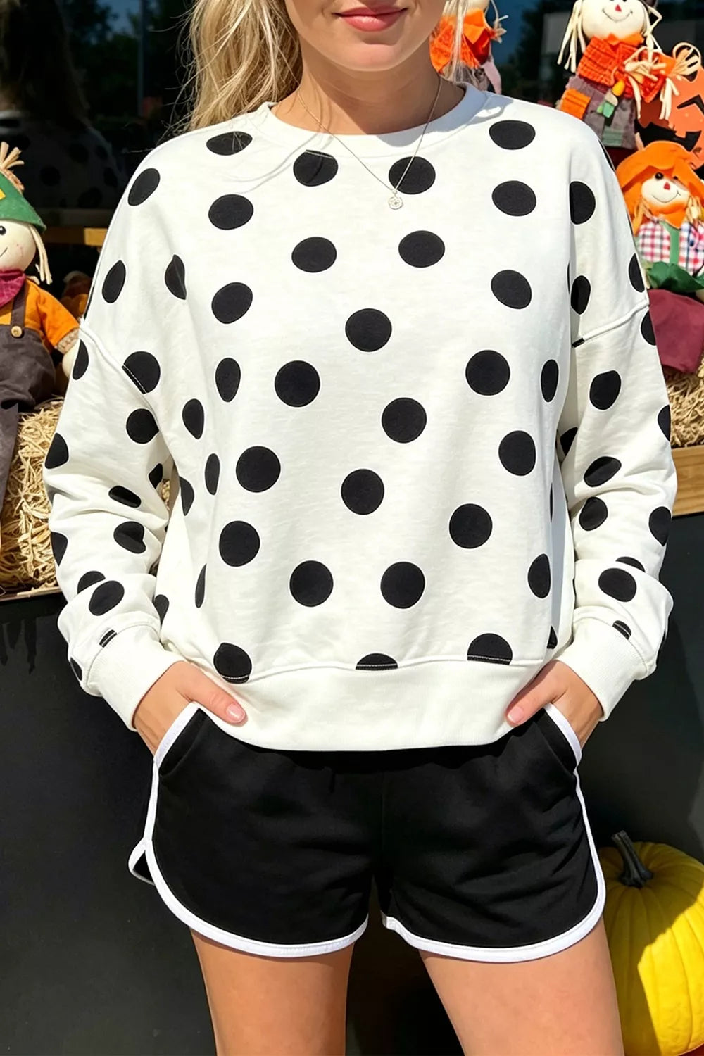 White pullover sweatshirt with black polka dots, round neck, long sleeves; ribbed details