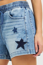 Denim shorts close-up with star patch, stitched seam, and drawstring waist