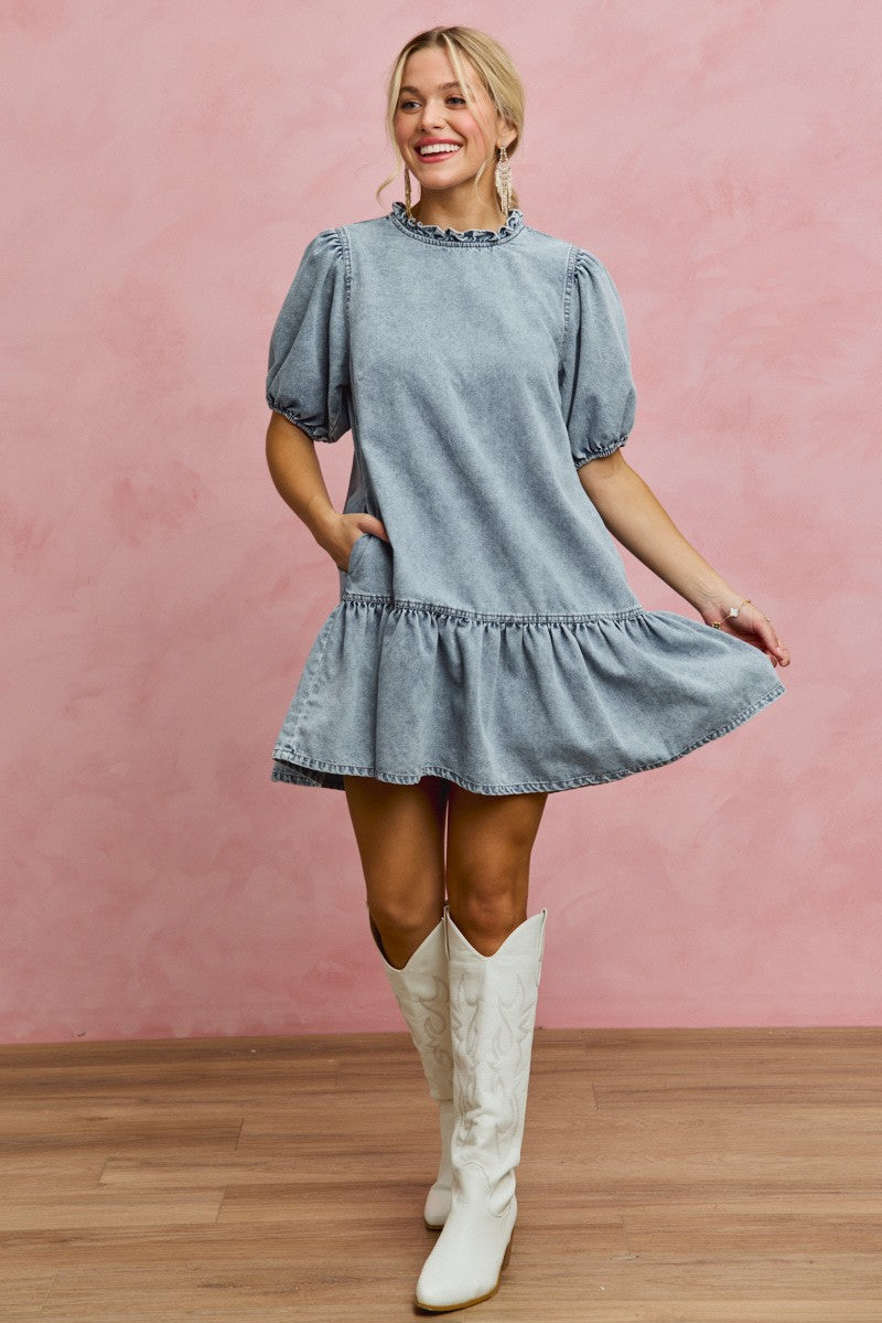 Light wash denim mini dress with ruffled high neck, puff sleeves, and flared tiered skirt