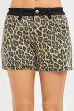 High-rise leopard-print shorts close-up: black waistband, front pockets, button closure