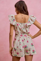 Back view of ivory floral print denim romper with cutout waist and ruffled shoulders