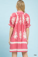 Back view of pink mini dress with white floral border print and gathered yoke