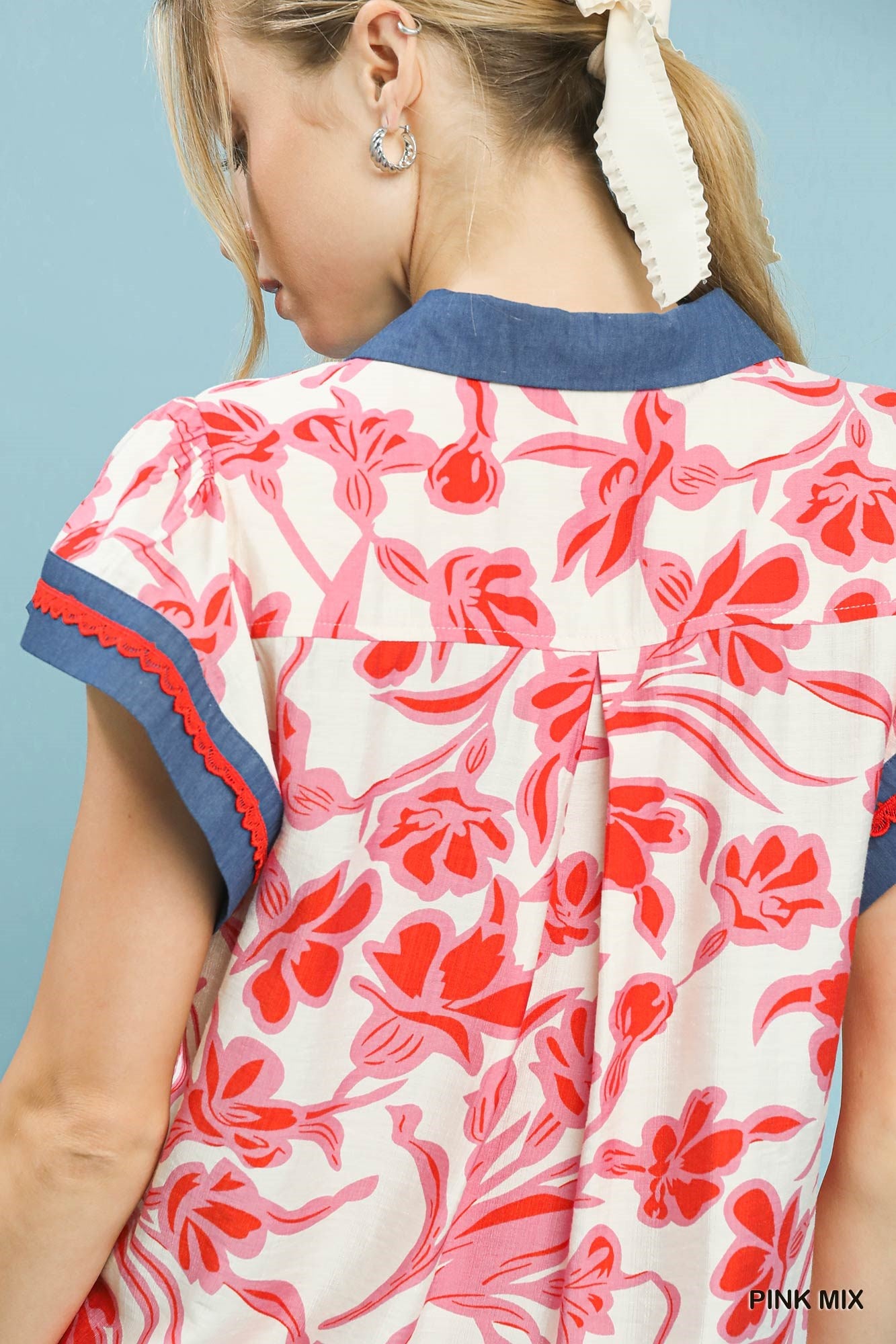Close-up back of floral flutter top with pink-and-white print and navy trim