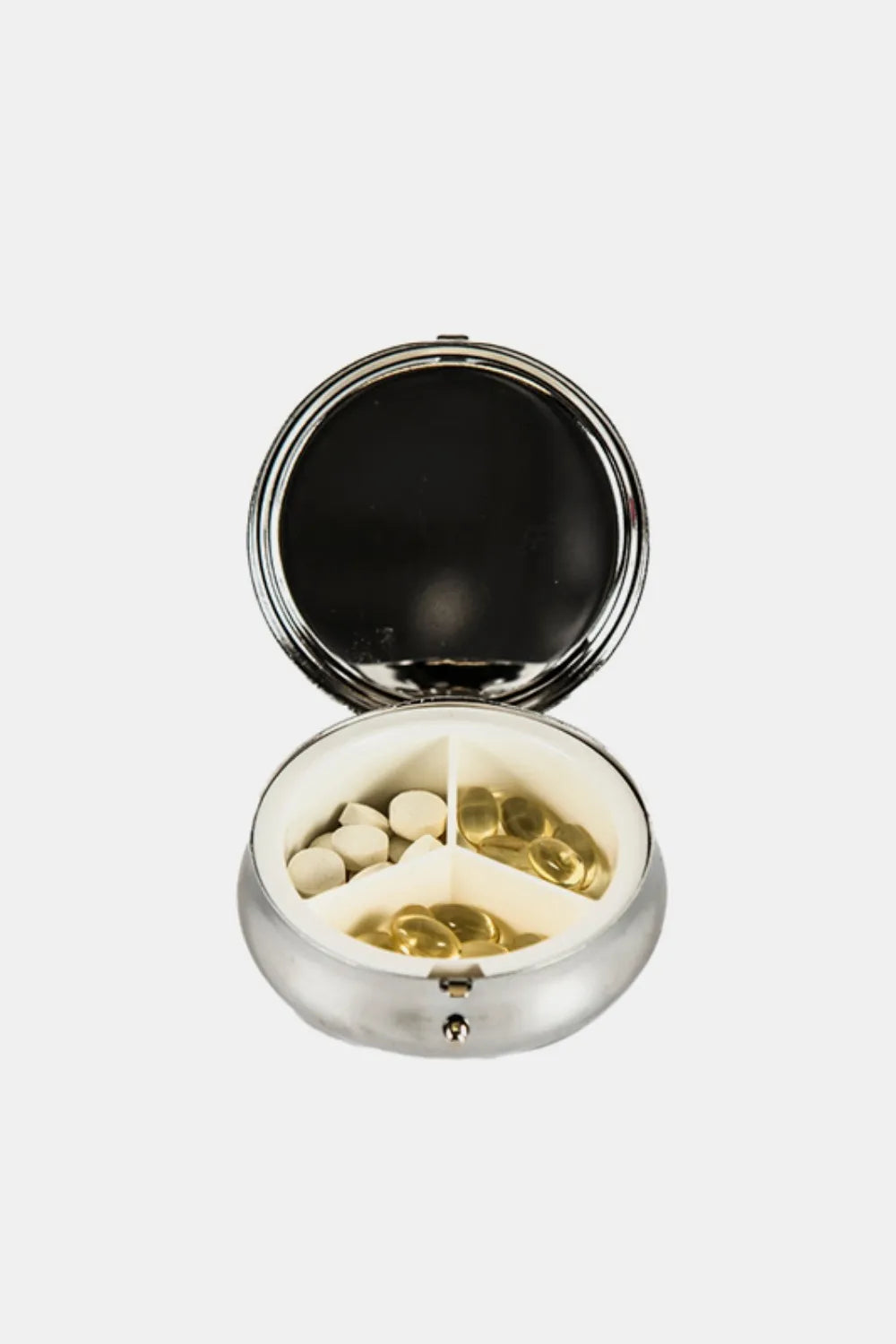 Silver-toned circular pill case opened, showing white pills and gold-toned capsules