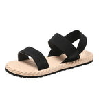 Women’s open-toe flat sandals with black knit cross straps and beige sole