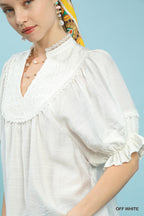 Off-white V-neck smocked yoke blouse with lace-trimmed neckline and puff sleeves
