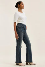 High-waist straight dark blue jeans with frayed hem and front pockets, side view