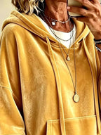 Yellow velvet hoodie close-up with hood, drawstring ties, and layered necklace look.