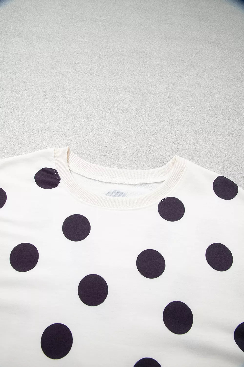 Close-up of white sweatshirt fabric with black polka dots and crew neckline
