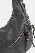 Close-up of black crescent shoulder bag with textured grain and silver-tone front zipper