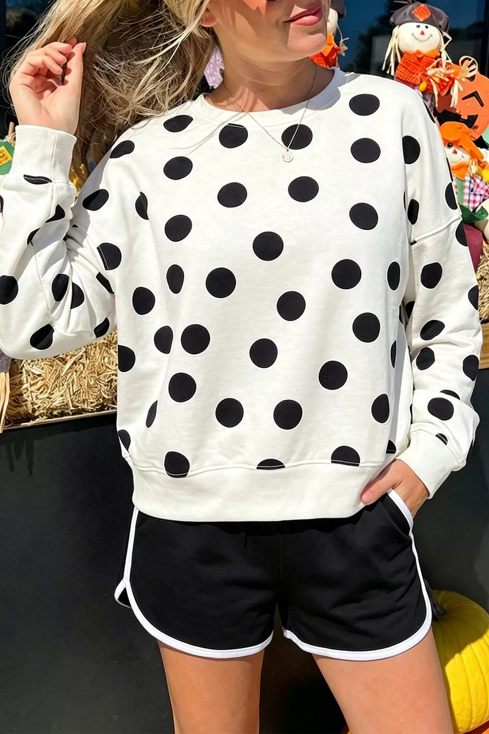 White round-neck sweatshirt with long sleeves and large black polka dots; ribbed cuffs