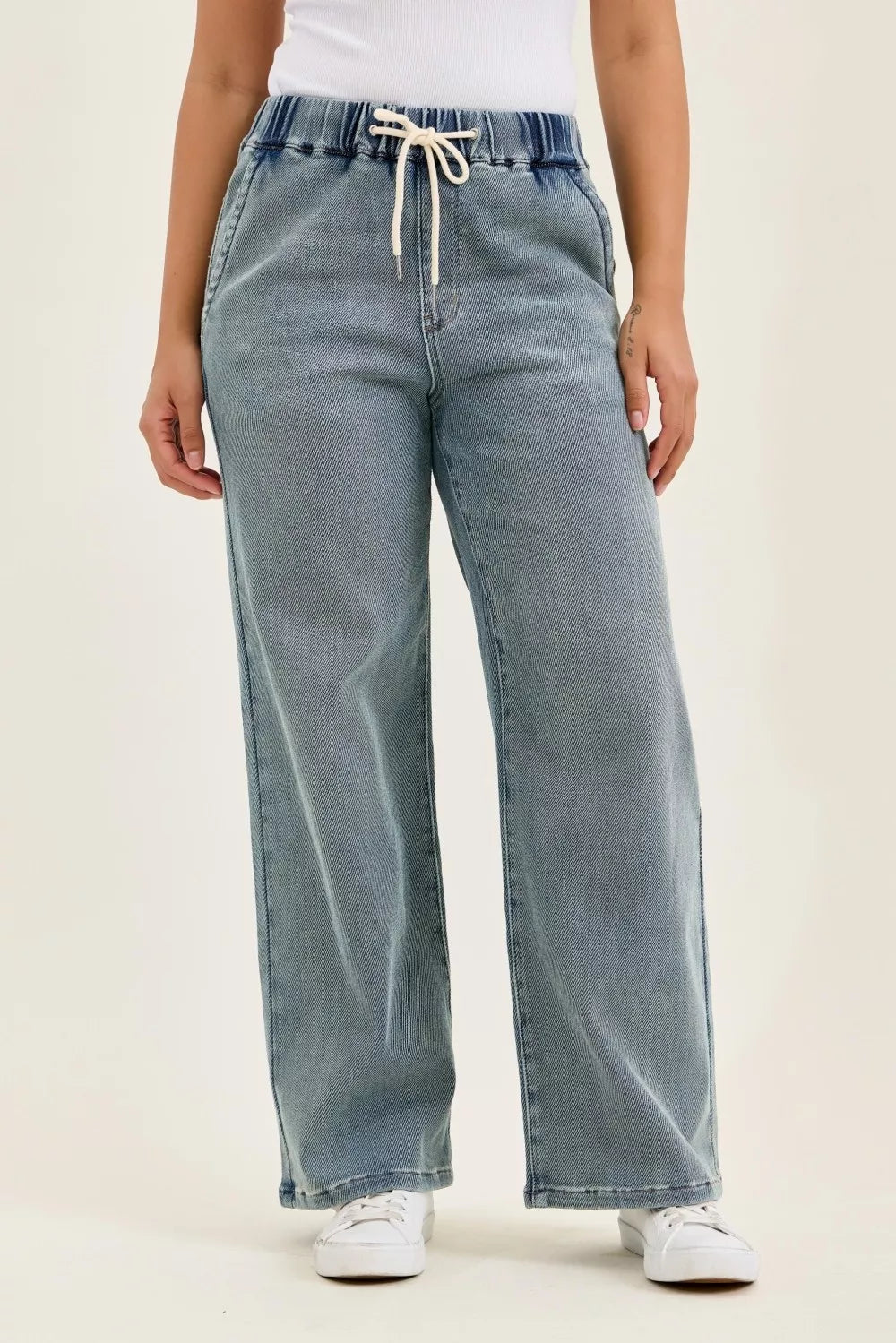 Medium-wash baggy jeans with elastic drawstring waist and wide straight legs