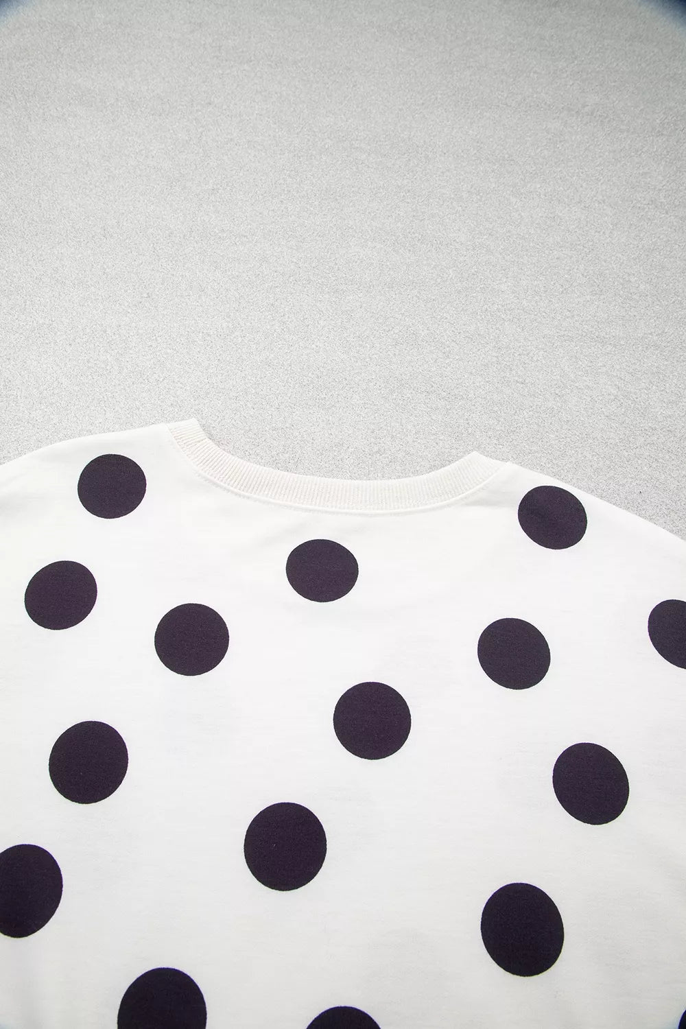 White sweatshirt close-up showing scattered black polka dots pattern