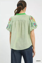 Back view of light green puff-sleeve top with floral embroidered sleeves